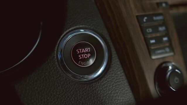 Man hand pushing start stop button in car. Close up male hand starting car with button. Male driver using start button in modern car.