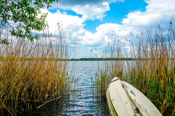 View of Lake Barleber with tall grass and a boat in the foreground. Lake near Magdeburg.
