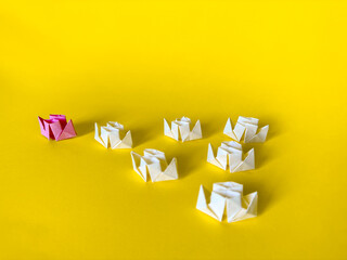 Origami boats. Group of white paper boats follow the pink one. Teamwork and leadership concept.