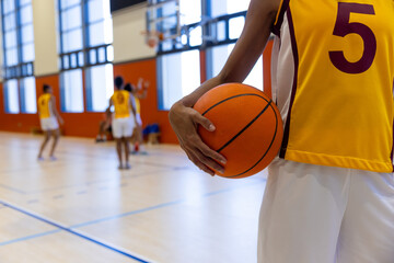 Naklejka premium Biracial female basketball players holding and playing basketball at gym, copy space