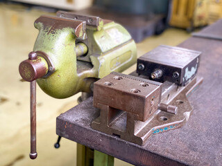 Old vise installed on table equipment for work in the factory