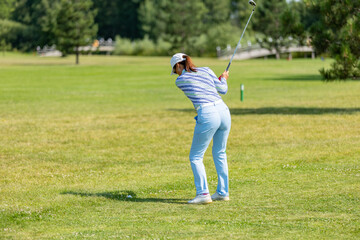 Professional woman golfer wearing golf wear teeing golf in golf tournament competition at golf course for winner.