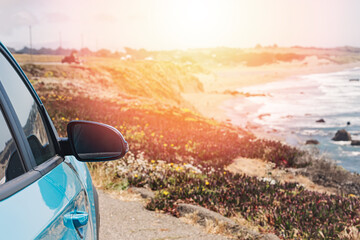 Blue car near the ocean with a warm glow, Road trip concept