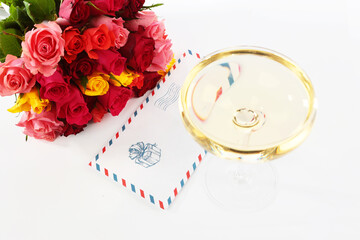 Wine glass and a bouquet of roses on a white background. Congratulations on the holiday in an envelope. Bouquet with roses on white background.