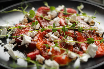 Baked red peppers with feta cheese and microgreens on a plate, close-up, macro
