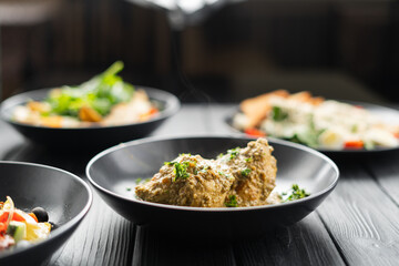 Chicken breast in a creamy garlic sauce on a plate on a black wooden table in a restaurant