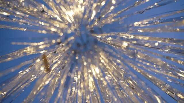 Silvery ribbons of tinsel are suspended under sky, which move with wind and shine, reflecting light of stage lighting. Festive silvery foil ribbons decorated for festive disco.
