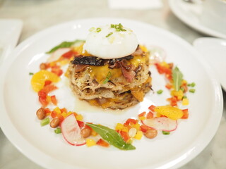 Fried rice with poached egg and vegetables in white plate.