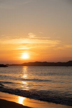 Intense orange and pink sunset above the water in Duli Beach, Palawan, Philippines. Sun going down, burning sky, golden hour.