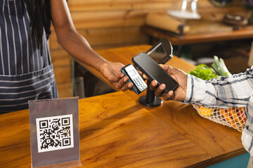 Midsection of senior african american man paying with smartphone at health food organic grocery shop