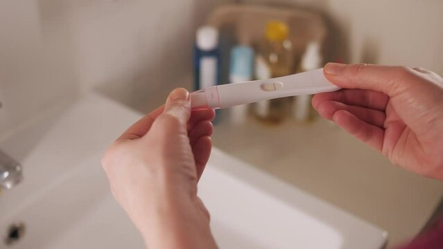 Woman with anxious feelings. Girl with a negative pregnancy test. Close-up of hands holding pregnancy test.