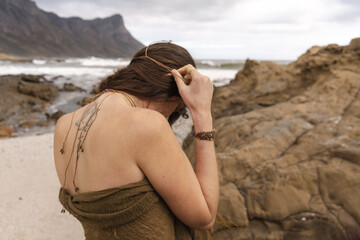 woman putting on a necklace at the beach