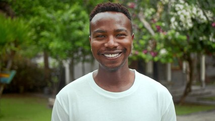 Happy african american look at camera. Dental white teeth. One 20s black person wear t-shirt. Cute guy face portrait. Fun mix race male. Nice man head shot. Cool afro hair. Stomatology smile close-up.
