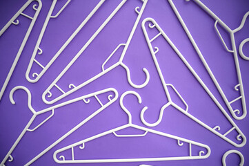 Creative top view, flat white hangers, purple background with copy space in minimalist style. Fashion women blog template for social media, sale, shop, promo design, shopping concept