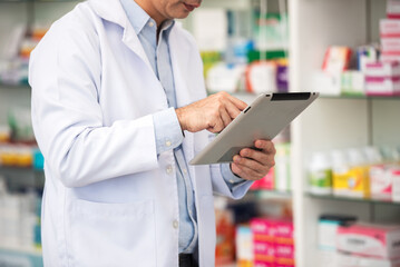 Close up pharmacist man using digital tablet for check medicine inventory in drug store, Medical service online, Telemedicine to giving medical information to online customer and patient.