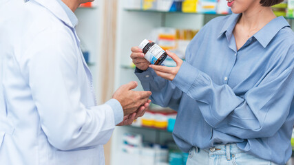 Asian man pharmacist advising and giving information to customer about medicine instructions in...
