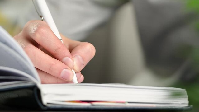 woman writes with a pen in a notebook close-up
