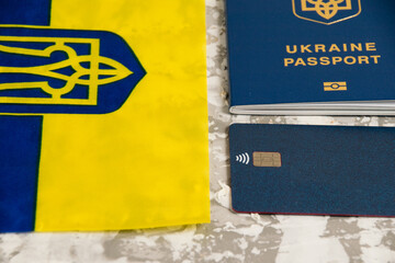 Flag of Ukraine with coat of arms, bank card and passport of a citizen of Ukraine on light gray background.