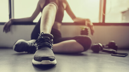 Concepts healthy lifestyle and workout. Bodybuilder, Workout, Fitness, Gym. Young asian woman sitting taking a break relaxing after exercise with a whey protein and dumbbell placed beside at gym.