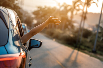 Road trip, Travel and vacation concepts. Happy woman hand out window car blue and driving on...