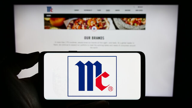 Stuttgart, Germany - 07-08-2023: Person holding smartphone with logo of US company McCormick Company Incorporated on screen in front of website. Focus on phone display.