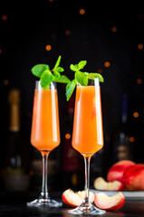 Peach Bellini alcoholic cocktail drink with prosecco, cava, or sparkling wine with peach puree, syrup and ice, dark bar counter background, copy space