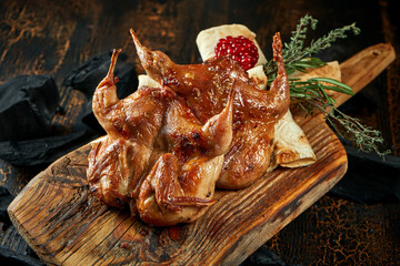 Quail roasted on a charcoal barbecue on a board.