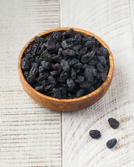 Dark blue raisins in a wooden bowl. Dried fruits, healthy snacks.