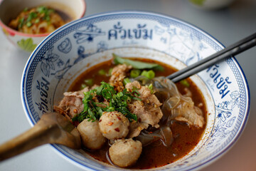 Thai noodles, spicy boat noodles with vegetables, free with crispy pork crackling Placed on a table...