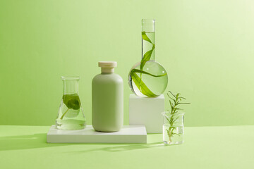 A green bottle unlabeled on white podiums with laboratory flask containing rosemary leaves, gotu...