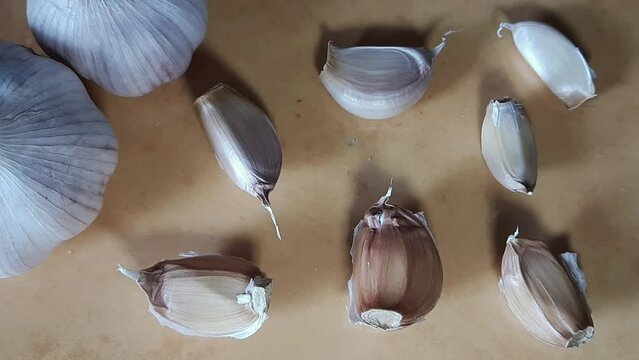 Close-up shot of garlic cloves on yellow background, top view.