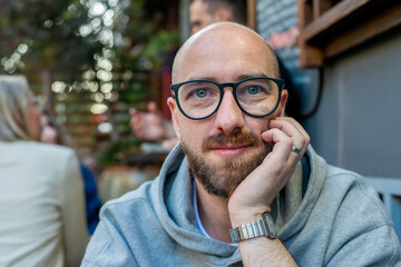 portrait of a handsome man with the glasses at the terrace of a restaurant in the evening