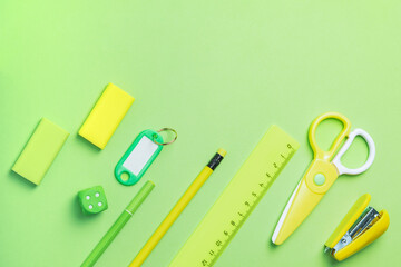 Yellow and green office supplies on a bright green background. Back to school.