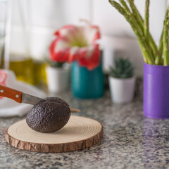 cutting a fresh avocado with a knife on a wooden board