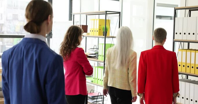 Female colleagues turn backs against defaulter male employee working in office. Concept of business rivalry and bullying in successful company slow motion