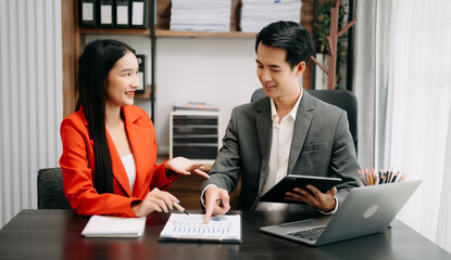 Asian business colleague business presents and explains and using laptop and tablet. Teamwork, financial marketing team,   while sitting in office room.