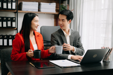 Asian business colleague business presents and explains and using laptop and tablet. Teamwork, financial marketing team,   while sitting in office room.