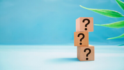Three wooden cubes with a question mark over a beautiful blue background with copy space. Trouble...