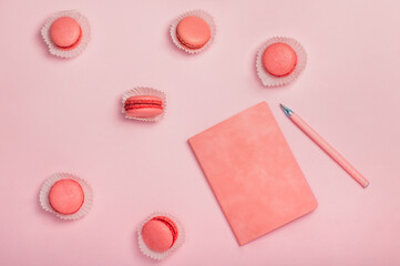 Flat lay composition with pink notebook, macaroons on pink background. Stylish women's workplace. Greeting card.