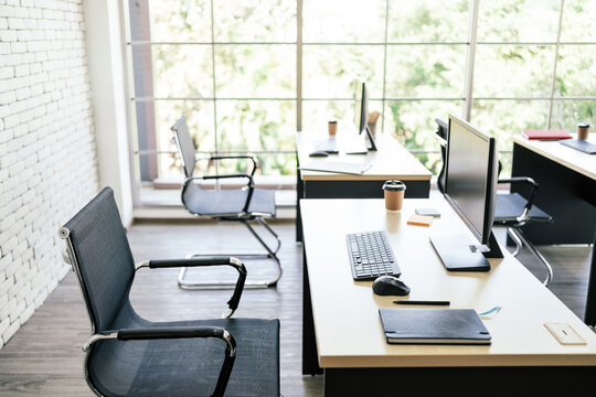 Mockup of modern personal desk office with monitor display, keyboard, mouse, notebook, pen and a paper coffee cup on the table in modern workspace. Image with copy space.