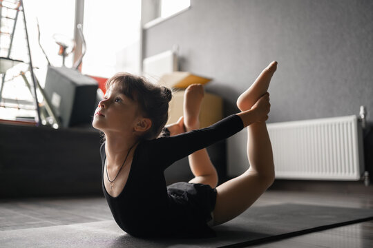 Small child girl doing stretching exercises Bow pose, gymnastic and dancing training class.