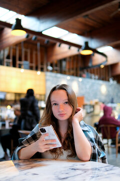 Girl texting on the smart phone in a restaurant terrace with an unfocused background. High quality photo