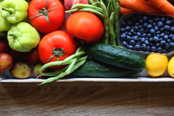 Wooden crate full of healthy seasonal fruit and vegetable. Top view, wooden background.