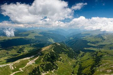 Fototapeta na wymiar Beautiful roads of Romania. Aerial photo with Transalpina road on top of the mountains with big clouds above. Curved waving road.