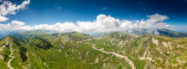 Beautiful roads of Romania. Aerial landscape photo with Transalpina road on top of the mountains with big clouds above. Curved waving road.