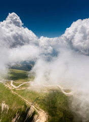 Beautiful roads of Romania. Aerial landscape photo with Transalpina road on top of the mountains with big clouds above. Curved waving road.