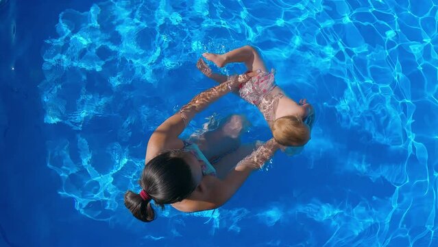 Mom and daughter swim in the pool