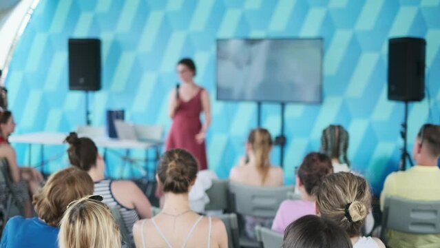 Anonymous woman speaking on stage during business meeting with colleagues