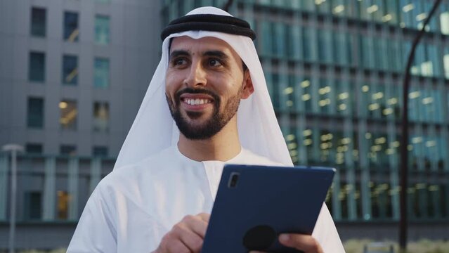 Handsome businessman with the traditional emirates white outfit working outdoor in Dubai city. Concept about middle eastern cultures and business