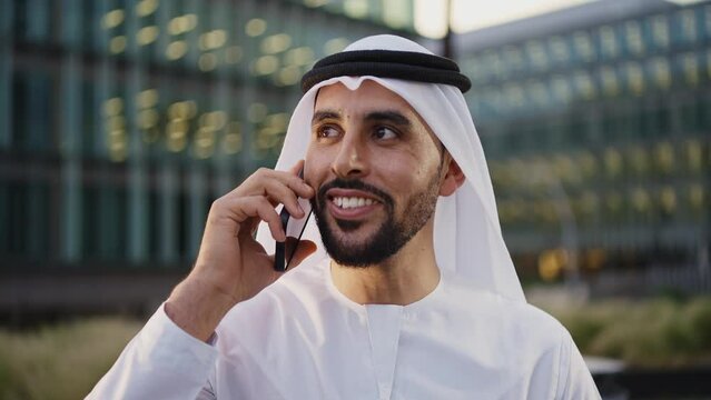 Handsome businessman with the traditional emirates white outfit working outdoor in Dubai city. Concept about middle eastern cultures and business